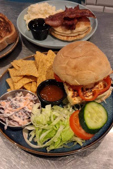 A halloumi and roasted pepper burger with nachos, coleslaw, salad and a sweet chilli pot