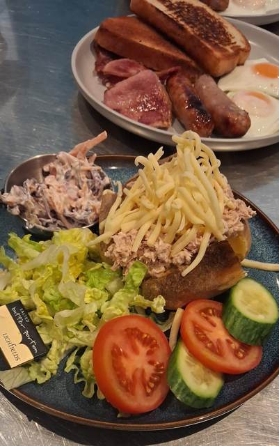 A jacket potato with tuna mayo and grated cheese, with coleslaw and salad